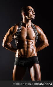 Muscular man with chain on black background