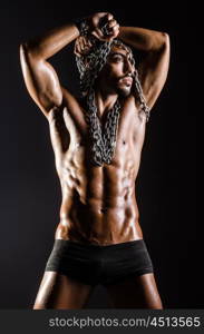 Muscular man with chain on black background