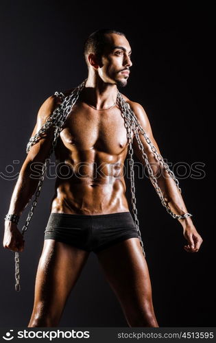 Muscular man with chain on black background