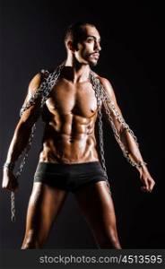 Muscular man with chain on black background