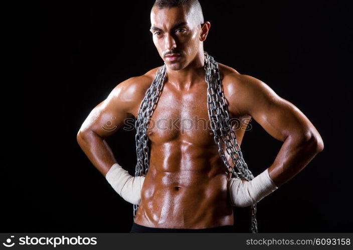 Muscular man with chain on black background