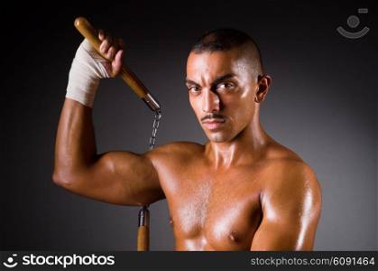 Muscular man with nunchucks on white