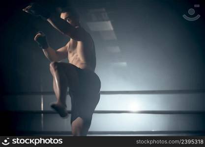 Muscular MMA fighter practicing kick, fight club concept. High quality photo. Muscular MMA fighter practicing kick, fight club concept.