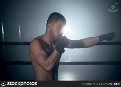 Muscular MMA fighter practicing punch, fight club concept. High quality photo. Muscular MMA fighter practicing punch, fight club concept.