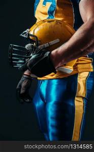 Muscular player with american football helmet in hand. Contact sport. Player with american football helmet in hand