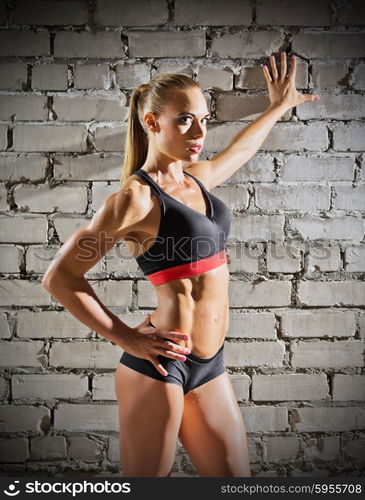 Muscular woman on grey brick wall background (normal version)