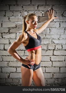 Muscular woman on grey brick wall background (normal version)