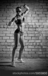 Muscular woman on grey brick wall (monochrome version)