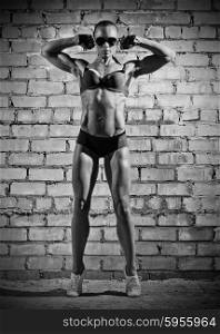 Muscular woman on grey brick wall (monochrome version)