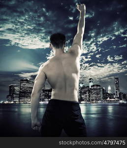 Muscular young athlete over the city background