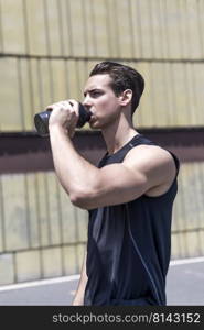 Muscular young male drinking water after workout