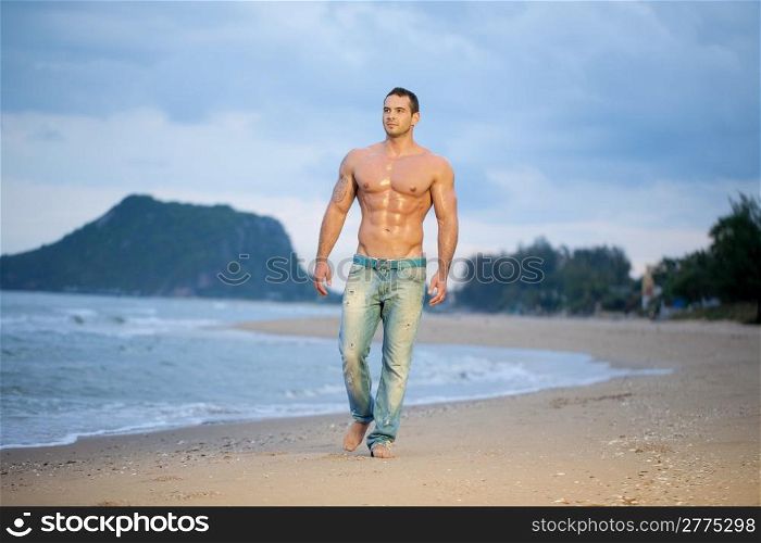 Muscular young male walking along a beach