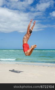 muscular young man jumping on the beach