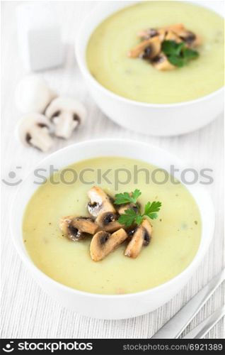 Mushroom cream soup garnished with roasted mushroom slices and parsley, photographed with natural light (Selective Focus, Focus in the middle of the first soup). Mushroom Cream Soup