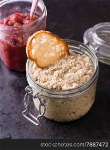 Mushroom pate and cranberry relish in a jars over dark background, selective focus