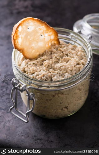 Mushroom pate in a jar over dark background, selective focus, copy space