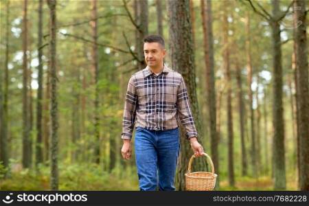 mushroom picking season and leisure people concept - happy middle aged man with wicker basket walking in autumn forest. happy man with basket picking mushrooms in forest