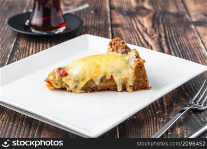 Mushroom quiche pie with tea on white plate on wooden table