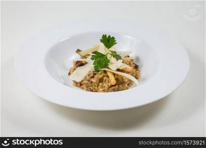 Mushroom risotto with parmesan in a white bowl on a white background