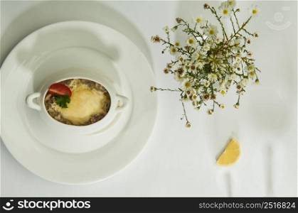 mushroom soup with lemon slices on a white surface with the shadow of wine glasses. food in a dish on a white surface