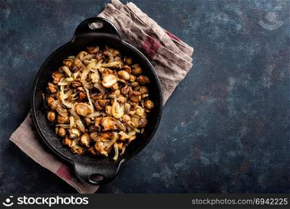 Mushrooms champignon fried with onion in pan, top view