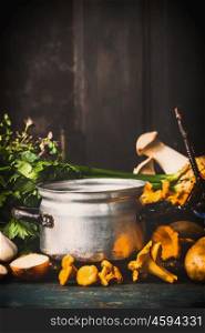 Mushrooms cooking with fresh herbs and Chanterelles on dark rustic kitchen table at wooden background, side view