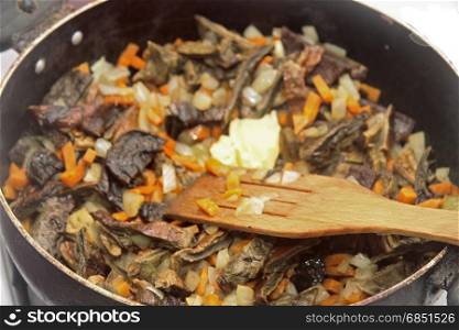 Mushrooms fried on the pan with carrot and onion