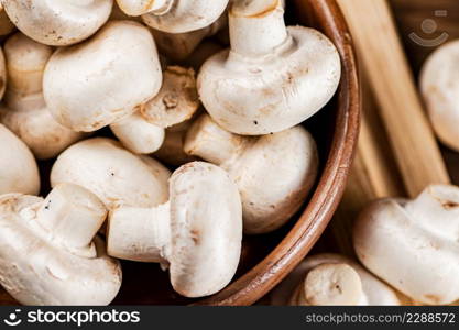 Mushrooms in a bowl on a cutting board. On a wooden background. High quality photo. Mushrooms in a bowl on a cutting board.