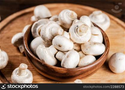 Mushrooms in a bowl on a cutting board. On a wooden background. High quality photo. Mushrooms in a bowl on a cutting board.