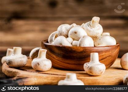Mushrooms in a bowl on a cutting board. On a wooden background. High quality photo. Mushrooms in a bowl on a cutting board.