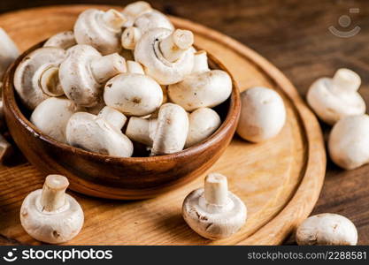 Mushrooms in a bowl on a cutting board. On a wooden background. High quality photo. Mushrooms in a bowl on a cutting board.