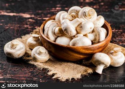 Mushrooms in a wooden plate on a napkin. Against a dark background. High quality photo. Mushrooms in a wooden plate on a napkin.