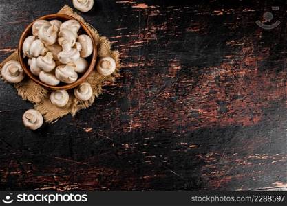 Mushrooms in a wooden plate on a napkin. Against a dark background. High quality photo. Mushrooms in a wooden plate on a napkin.