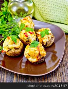 Mushrooms stuffed with meat with parsley and pepper in a brown plate green towel on a wooden boards background