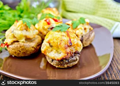 Mushrooms stuffed with meat with parsley in a brown plate green kitchen towel on the background of wooden boards