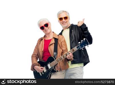 music, age and people concept - happy senior couple in sunglasses with electric guitar showing thumbs up. happy senior couple with guitar showing thumbs up