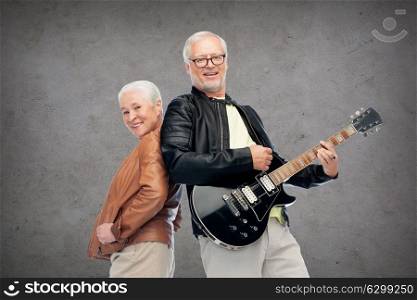 music, age and people concept - happy senior couple with electric guitar over concrete background. happy senior couple with electric guitar