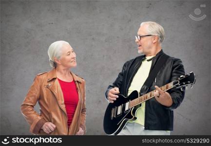 music, age and people concept - happy senior couple with electric guitar over gray background. happy senior couple with electric guitar