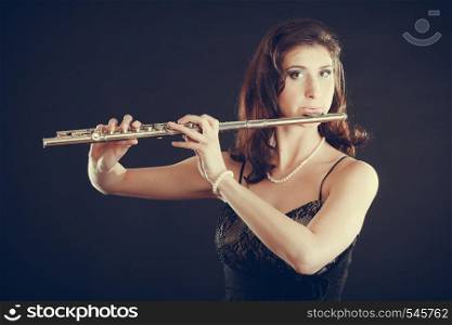 Music and elegance. Alluring elegant woman playing on transverse flute. Female musician with her instrument performing.. Woman playing transverse flute on black.