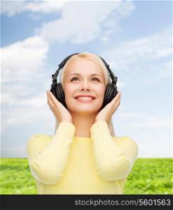 music and technology concept - smiling young woman listening to music with headphones