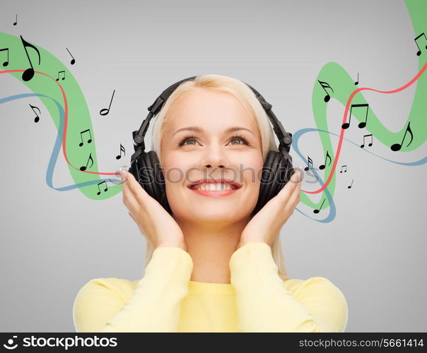 music and technology concept - smiling young woman listening to music with headphones