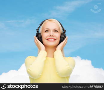 music and technology concept - smiling young woman listening to music with headphones