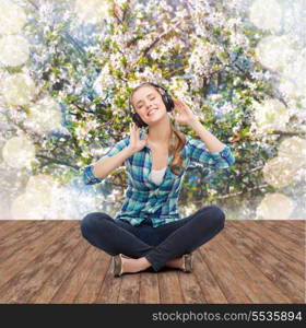 music and technology concept - smiling young woman sitting on floor and listeting to music with headphones