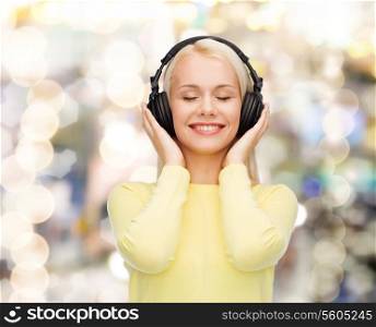 music and technology concept - smiling young woman with closed eyes listening to music with headphones