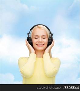 music and technology concept - smiling young woman with closed eyes listening to music with headphones