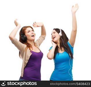 music and technology concept - two laughing teenagers with headphones dancing