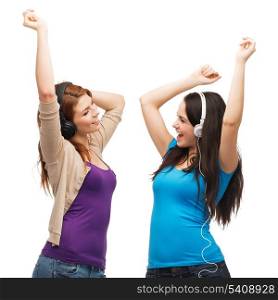 music and technology concept - two laughing teenagers with headphones dancing