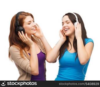 music and technology concept - two smiling teenagers with closed eyes listeting to music with headphones