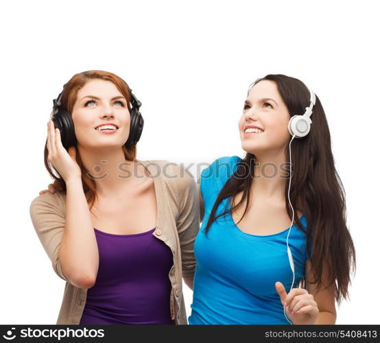 music and technology concept - two smiling teenagers with headphones looking up