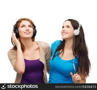 music and technology concept - two smiling teenagers with headphones looking up